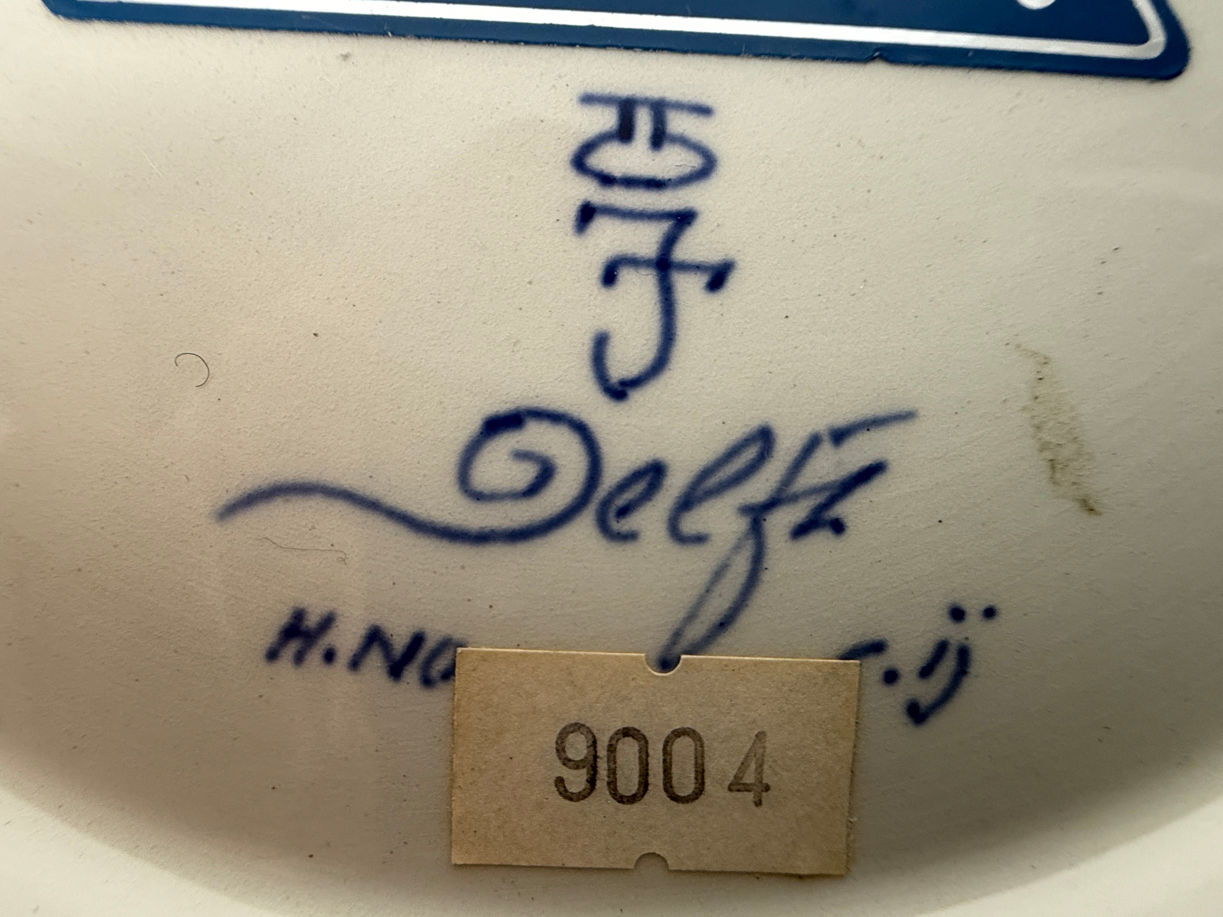 Close-up of a ceramic item with 'Delft' branding and a tag number '9004'.