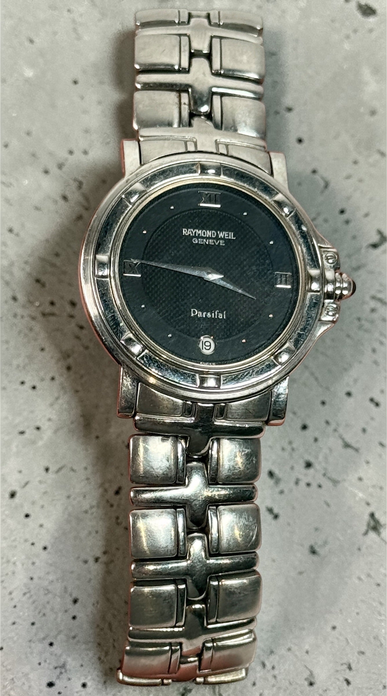 Raymond Weil Parsifal Swiss quartz watch with black dial, Roman numerals, and steel bracelet. Classic luxury design with date display, everyday wearable style.