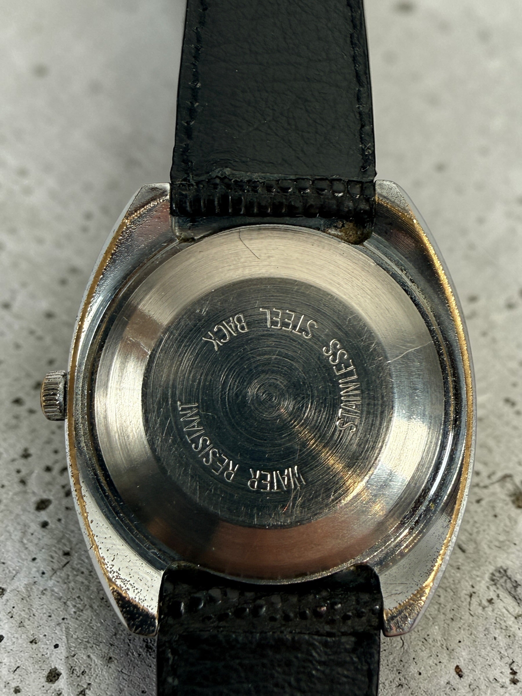 Vintage Timex automatic day-date watch with blue markers and 1970s cushion case design. Affordable mechanical wristwatch with classic retro style.