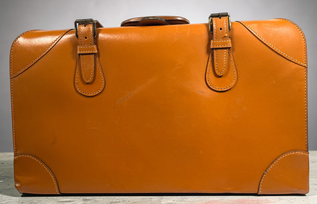 Vintage tan leather suitcase by Dionite Luggage. 1960s structured valise with brass hardware and interior compartments. Great for travel or decor.