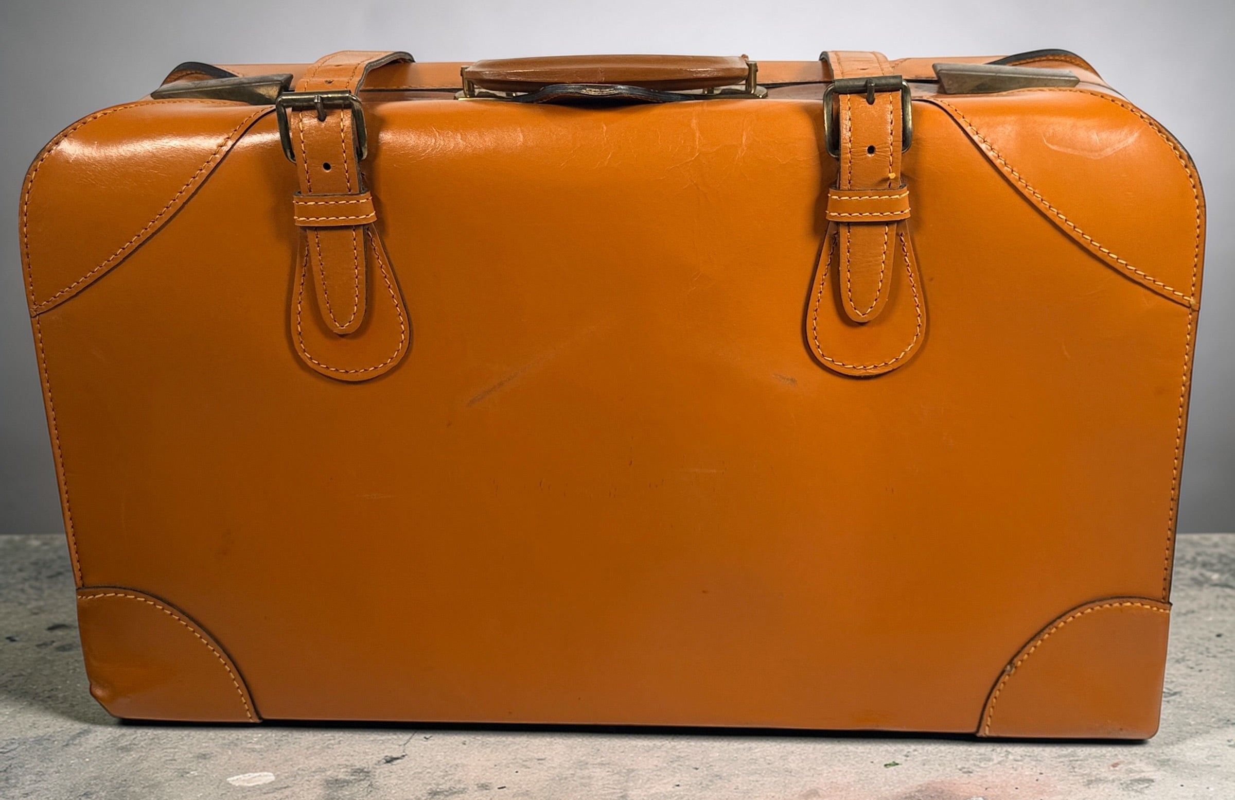 Vintage tan leather suitcase by Dionite Luggage. 1960s structured valise with brass hardware and interior compartments. Great for travel or decor.