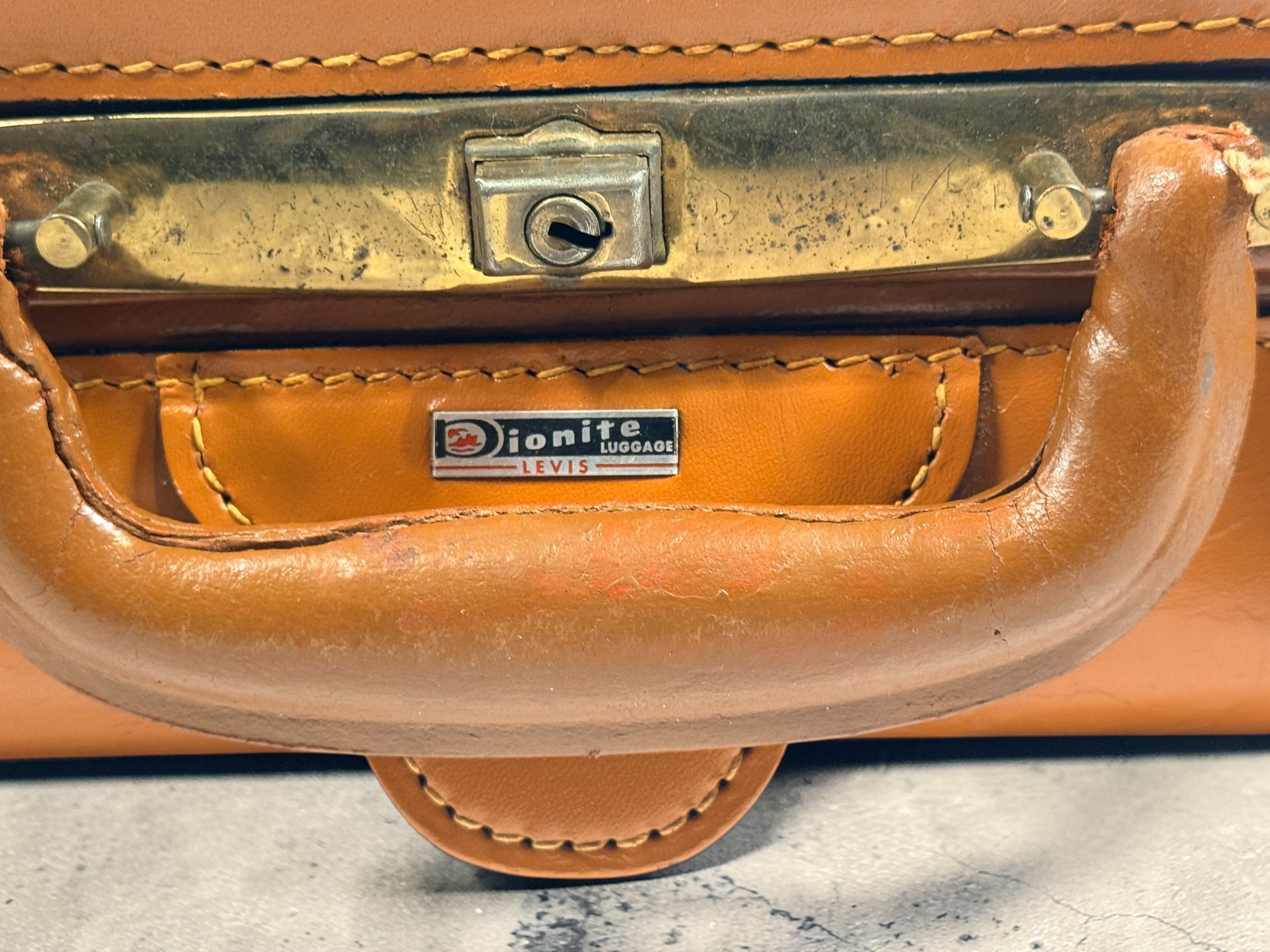 Vintage tan leather suitcase by Dionite Luggage. 1960s structured valise with brass hardware and interior compartments. Great for travel or decor.