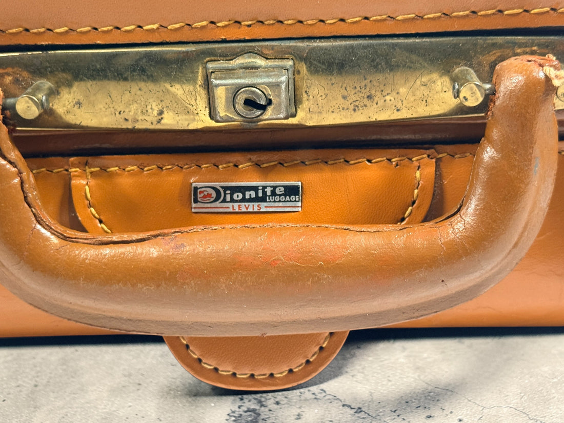 Vintage tan leather suitcase by Dionite Luggage. 1960s structured valise with brass hardware and interior compartments. Great for travel or decor.