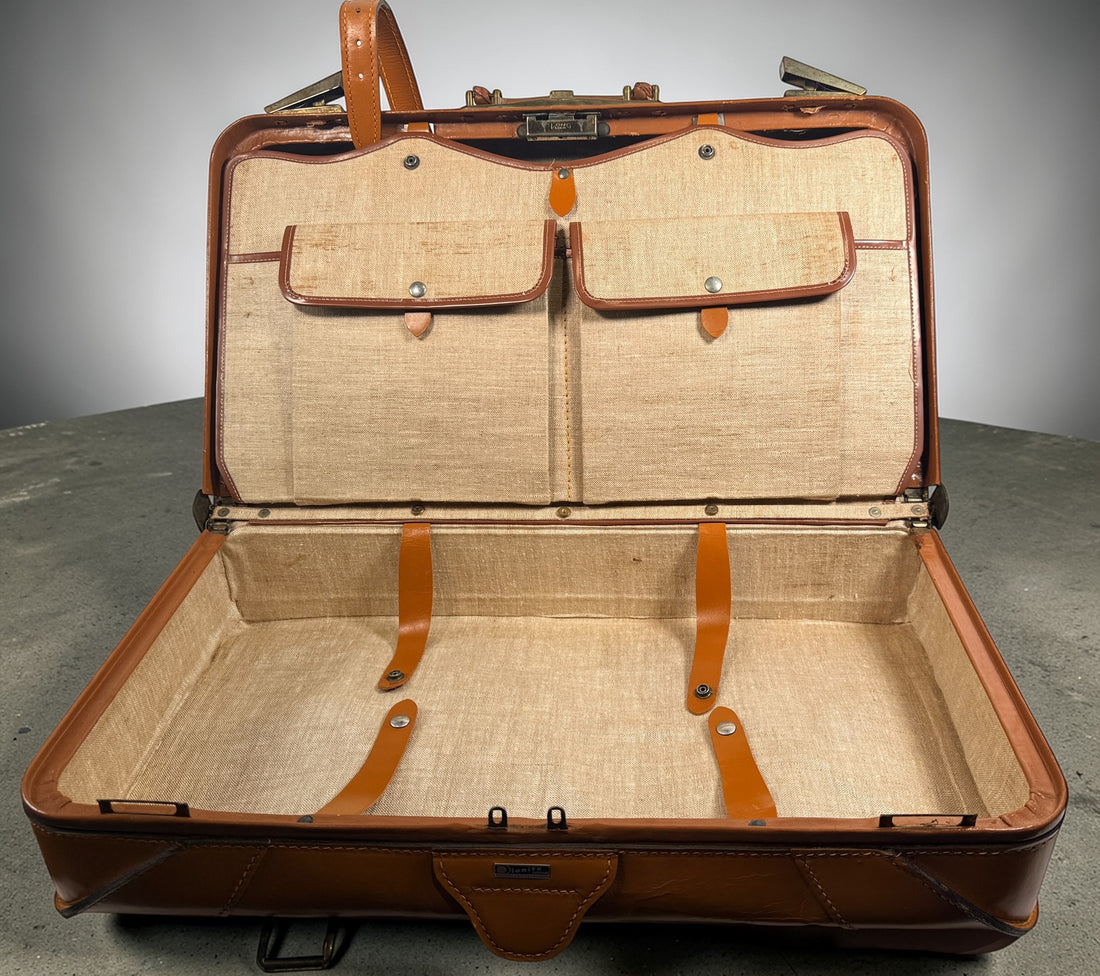 Vintage tan leather suitcase by Dionite Luggage. 1960s structured valise with brass hardware and interior compartments. Great for travel or decor.