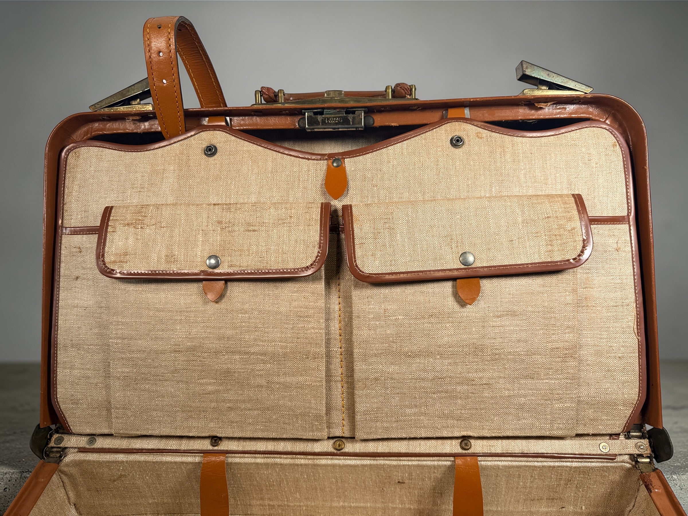 Vintage tan leather suitcase by Dionite Luggage. 1960s structured valise with brass hardware and interior compartments. Great for travel or decor.