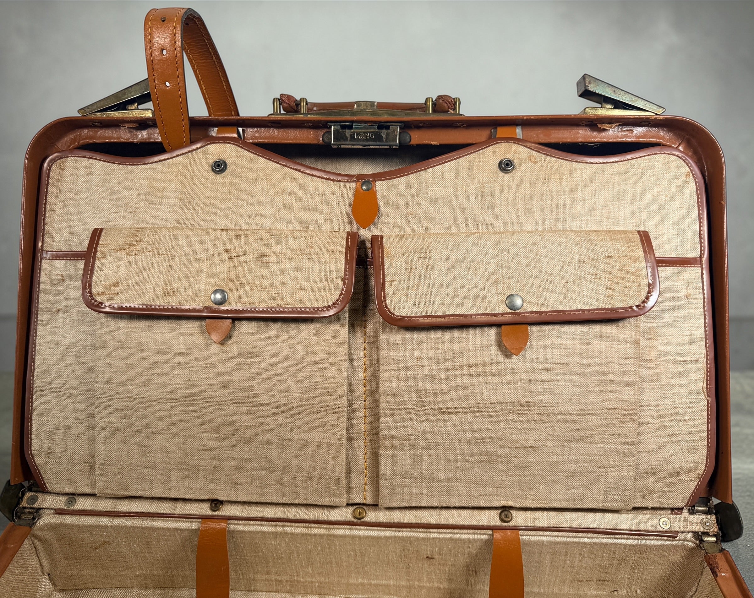 Vintage tan leather suitcase by Dionite Luggage. 1960s structured valise with brass hardware and interior compartments. Great for travel or decor.