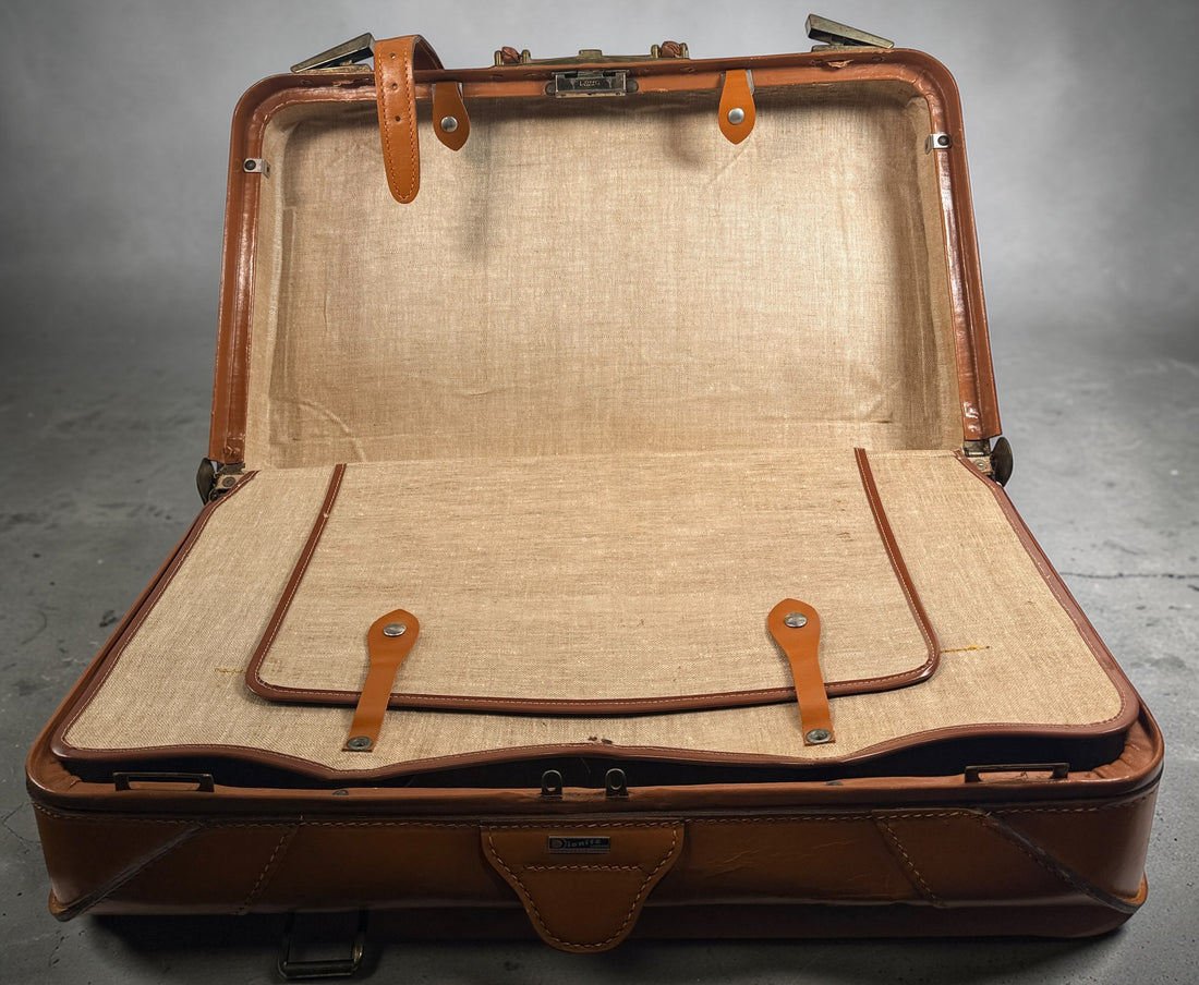 Vintage tan leather suitcase by Dionite Luggage. 1960s structured valise with brass hardware and interior compartments. Great for travel or decor.