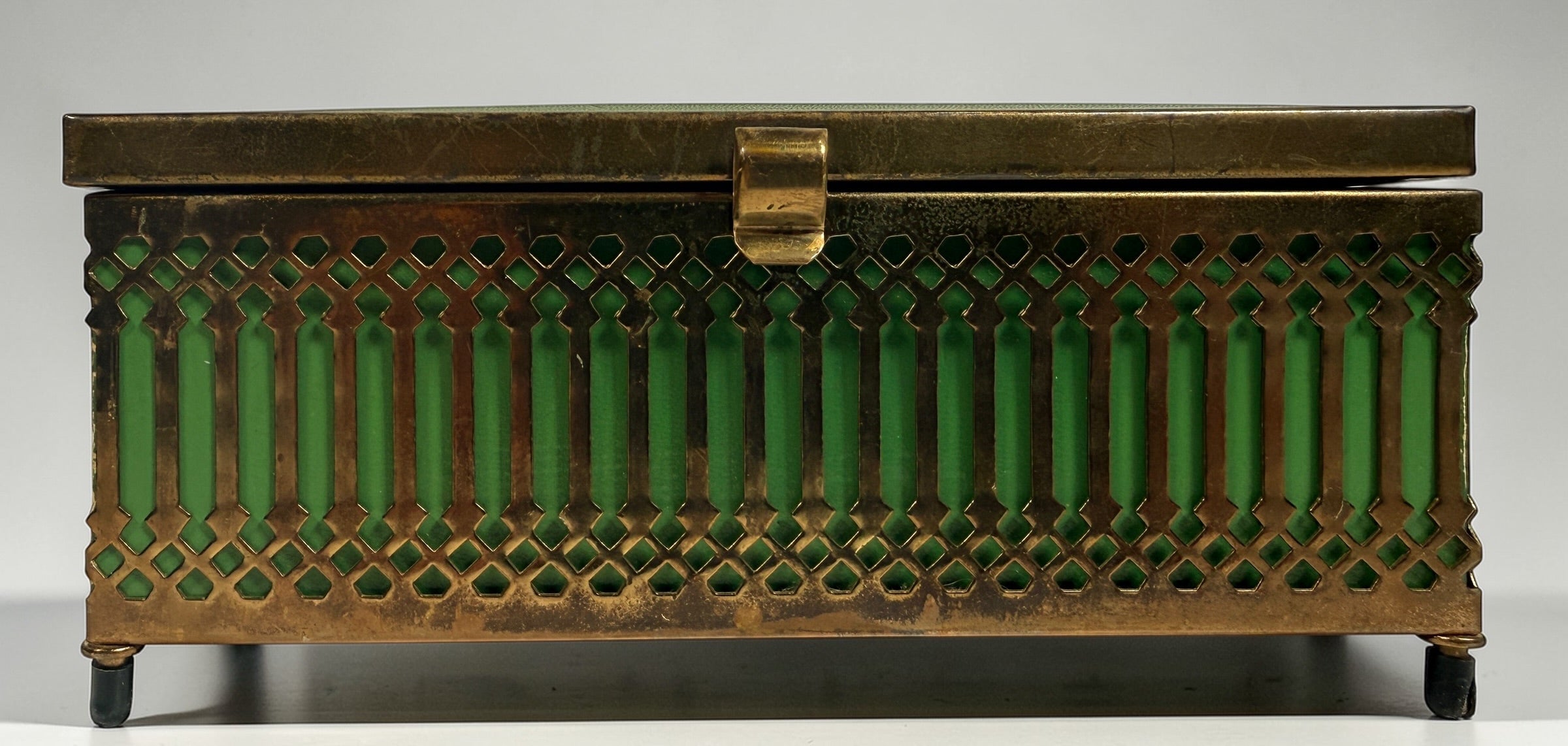 Vintage Mele Hollywood Regency jewelry box with brass filigree and green glass. Red velvet interior with compartments. Decorative mid-century piece.