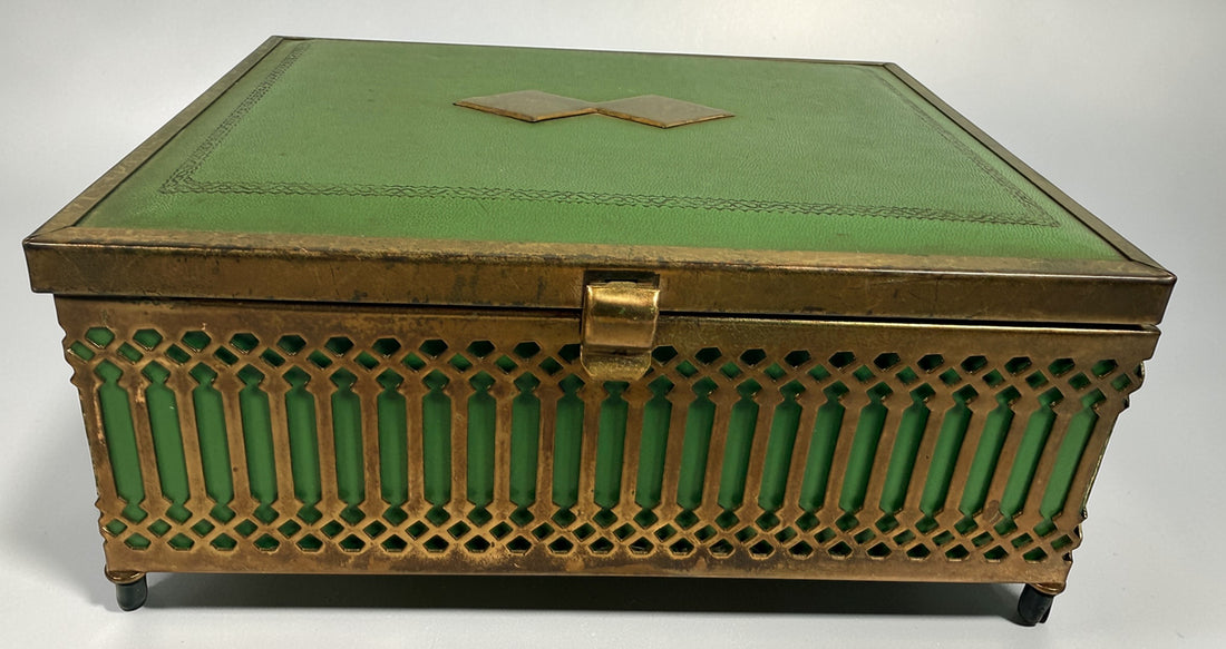 Vintage Mele Hollywood Regency jewelry box with brass filigree and green glass. Red velvet interior with compartments. Decorative mid-century piece.