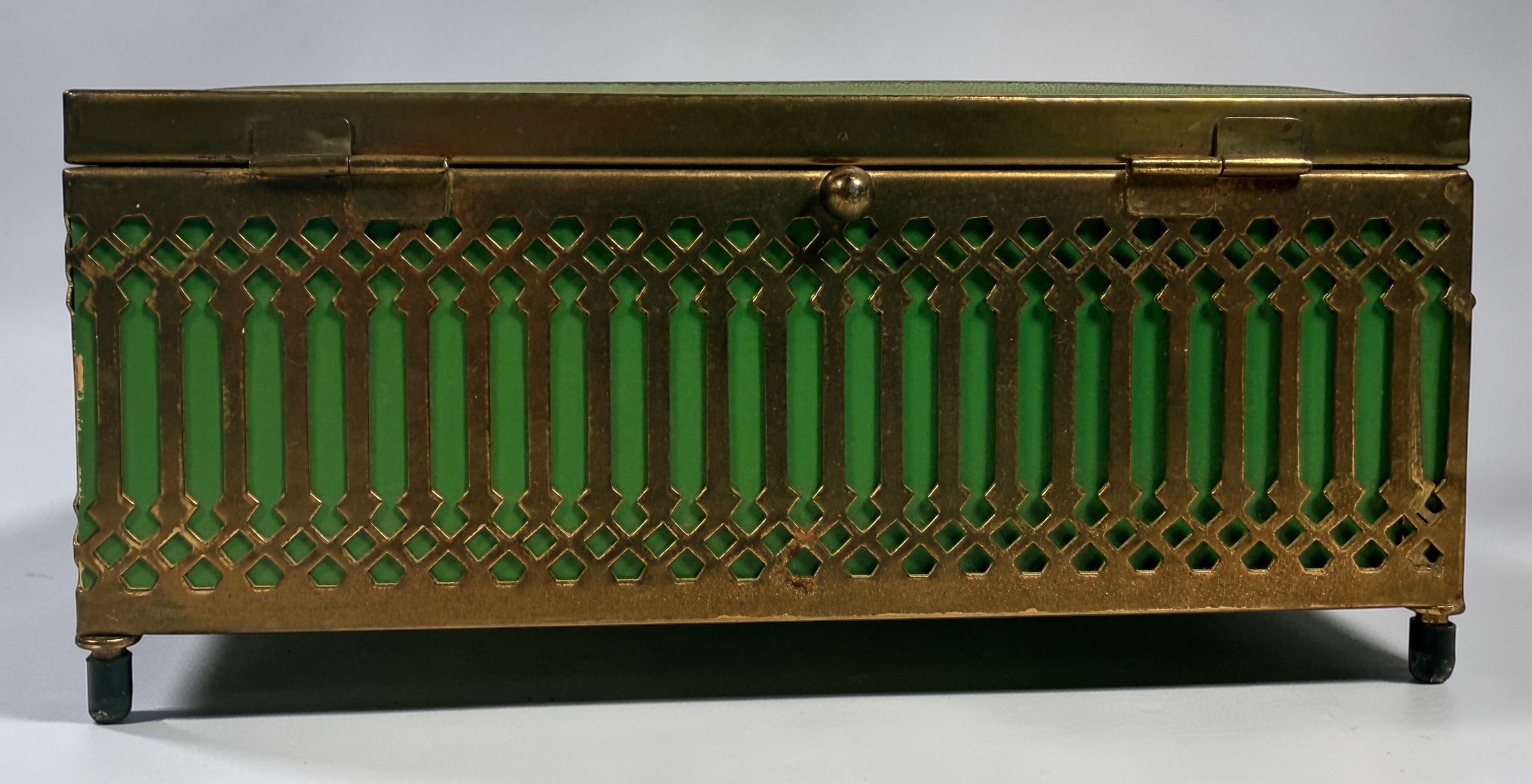 Vintage Mele Hollywood Regency jewelry box with brass filigree and green glass. Red velvet interior with compartments. Decorative mid-century piece.