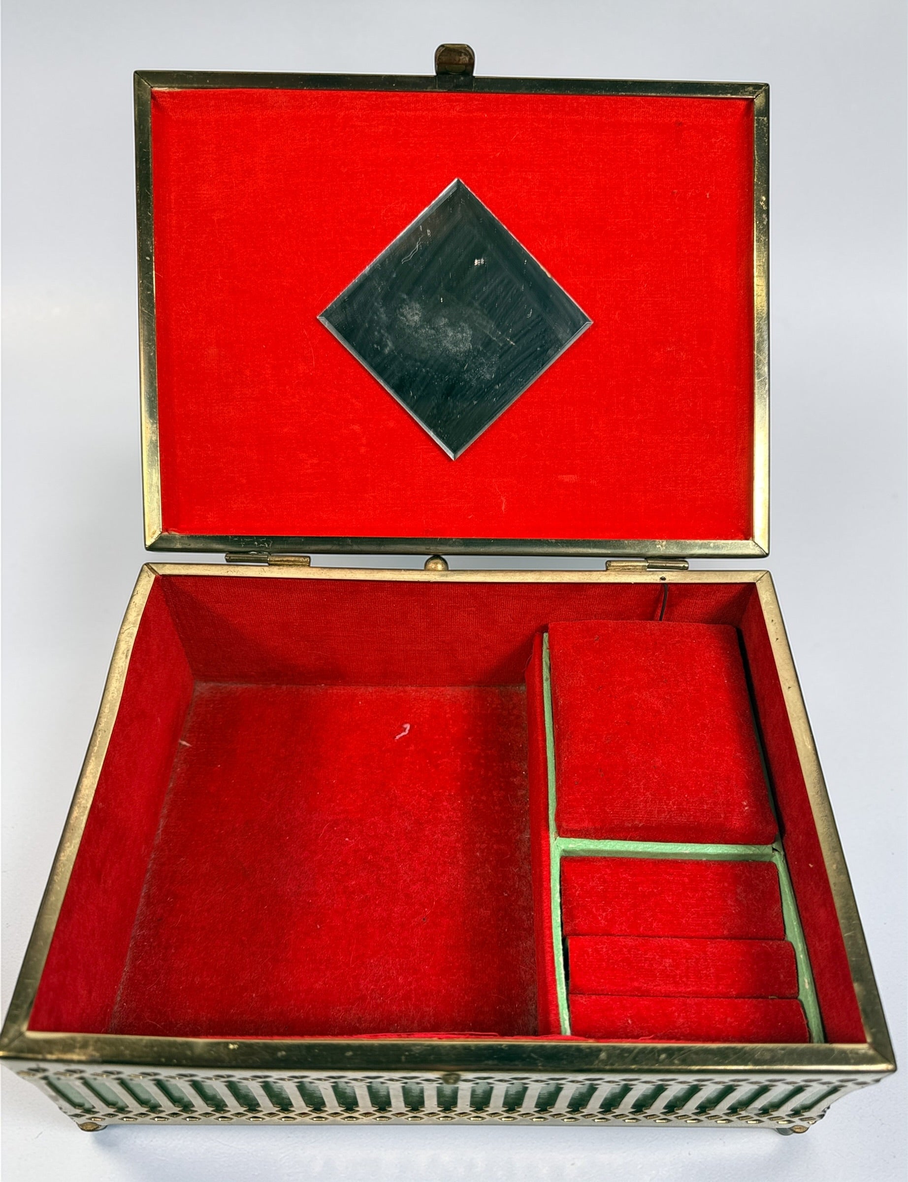Vintage Mele Hollywood Regency jewelry box with brass filigree and green glass. Red velvet interior with compartments. Decorative mid-century piece.