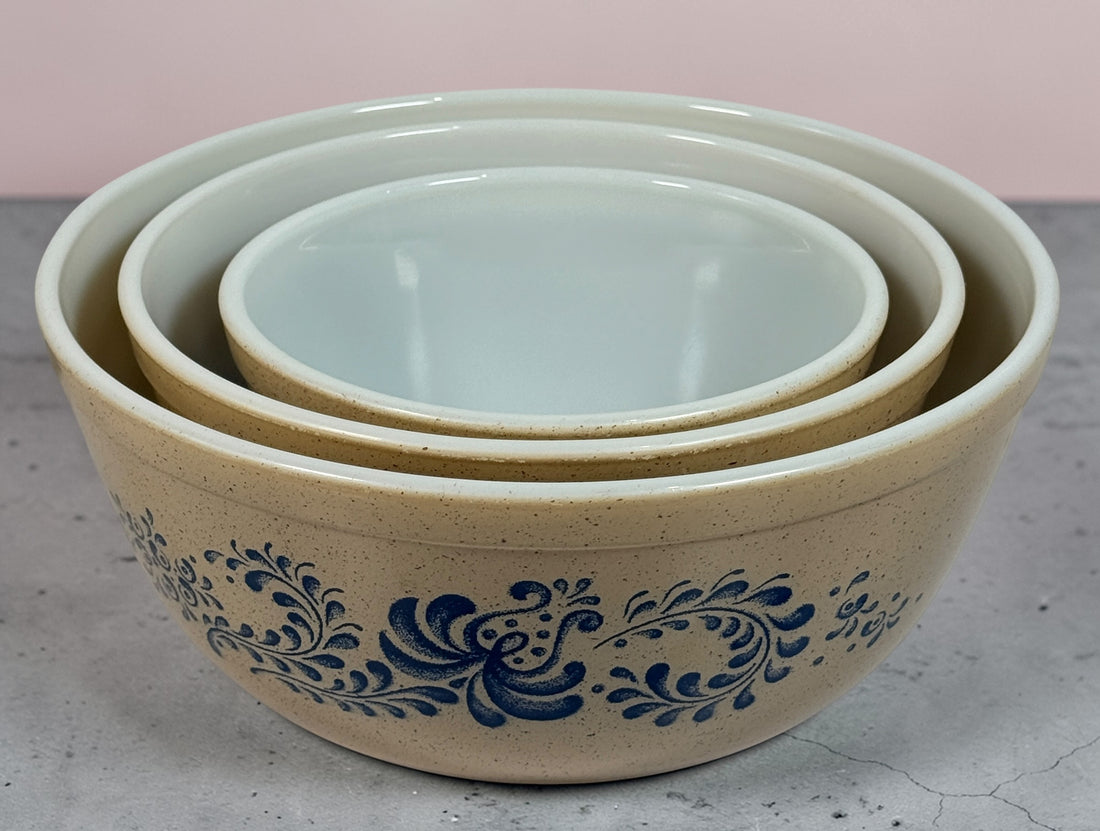 Vintage Pyrex Homestead blue floral mixing bowls and casserole dishes with lids. Classic farmhouse kitchenware set, durable glass, collectible and practical.