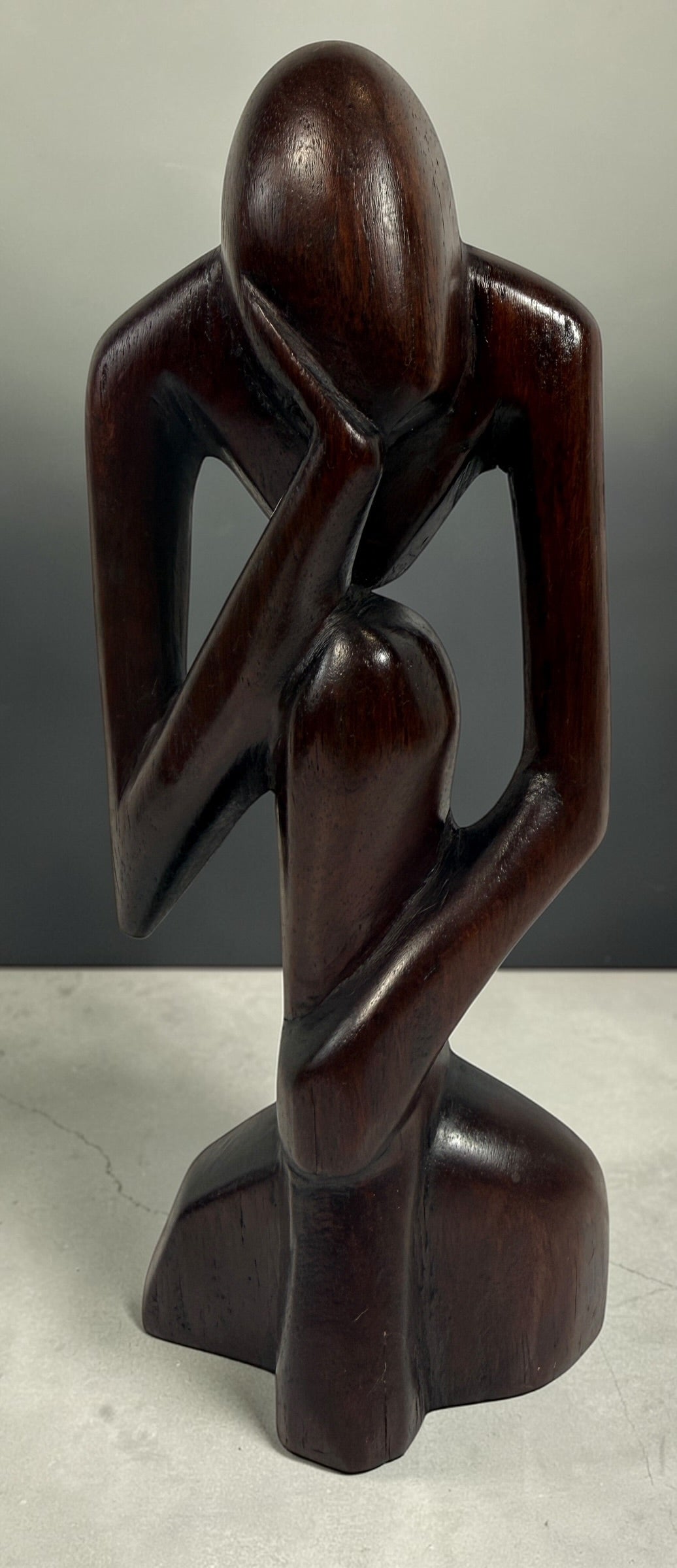 Hand-carved wooden thinker sculpture with mid-century modern style. Abstract decorative figure in dark hardwood, perfect for vintage or contemporary interiors.