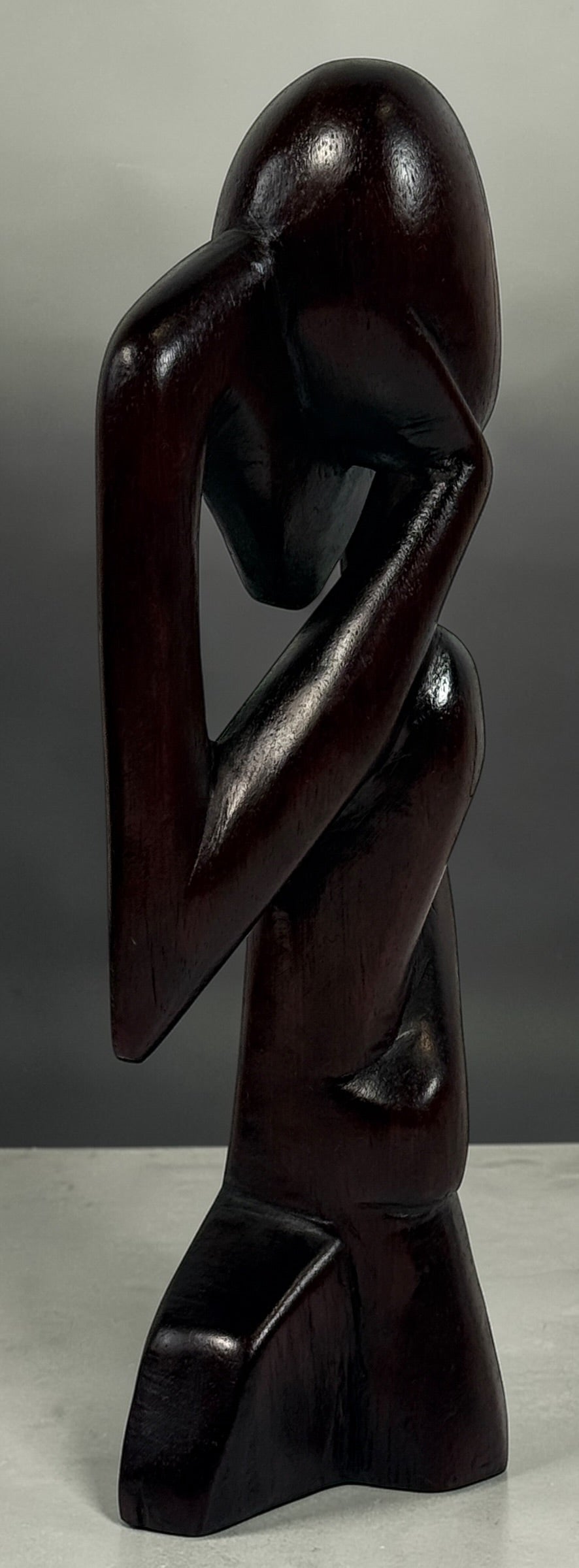 Hand-carved wooden thinker sculpture with mid-century modern style. Abstract decorative figure in dark hardwood, perfect for vintage or contemporary interiors.
