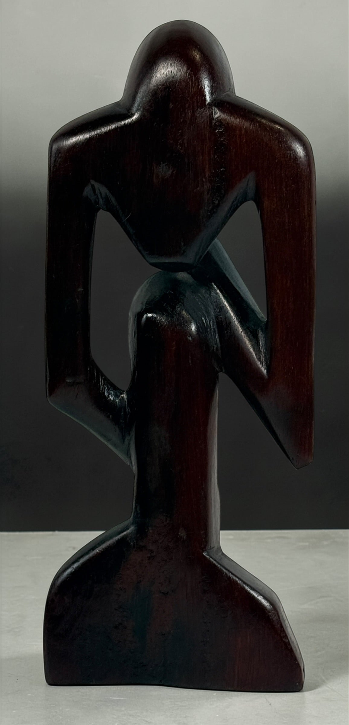 Hand-carved wooden thinker sculpture with mid-century modern style. Abstract decorative figure in dark hardwood, perfect for vintage or contemporary interiors.