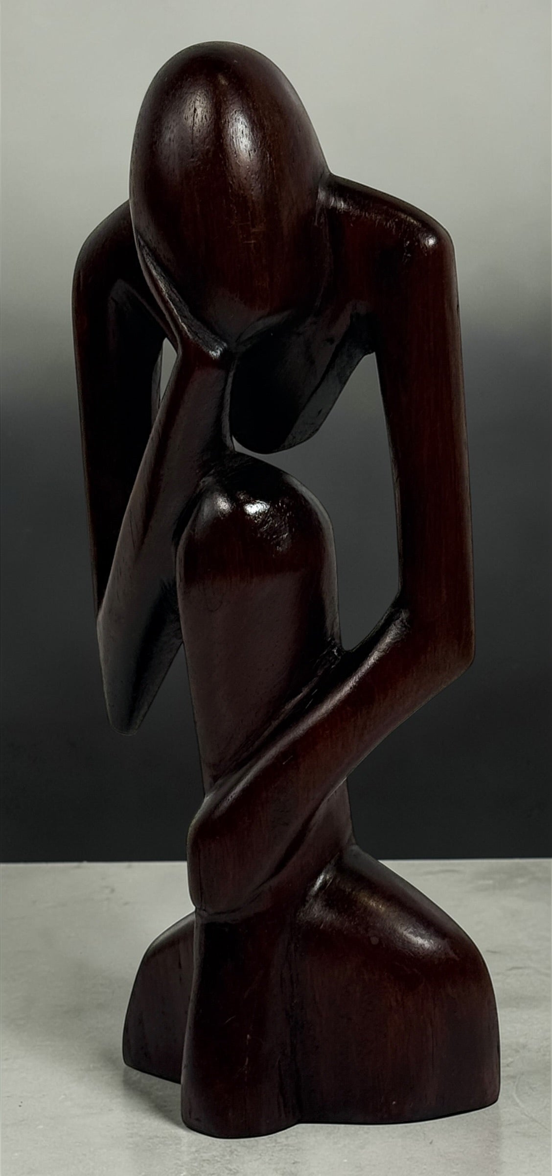 Hand-carved wooden thinker sculpture with mid-century modern style. Abstract decorative figure in dark hardwood, perfect for vintage or contemporary interiors.
