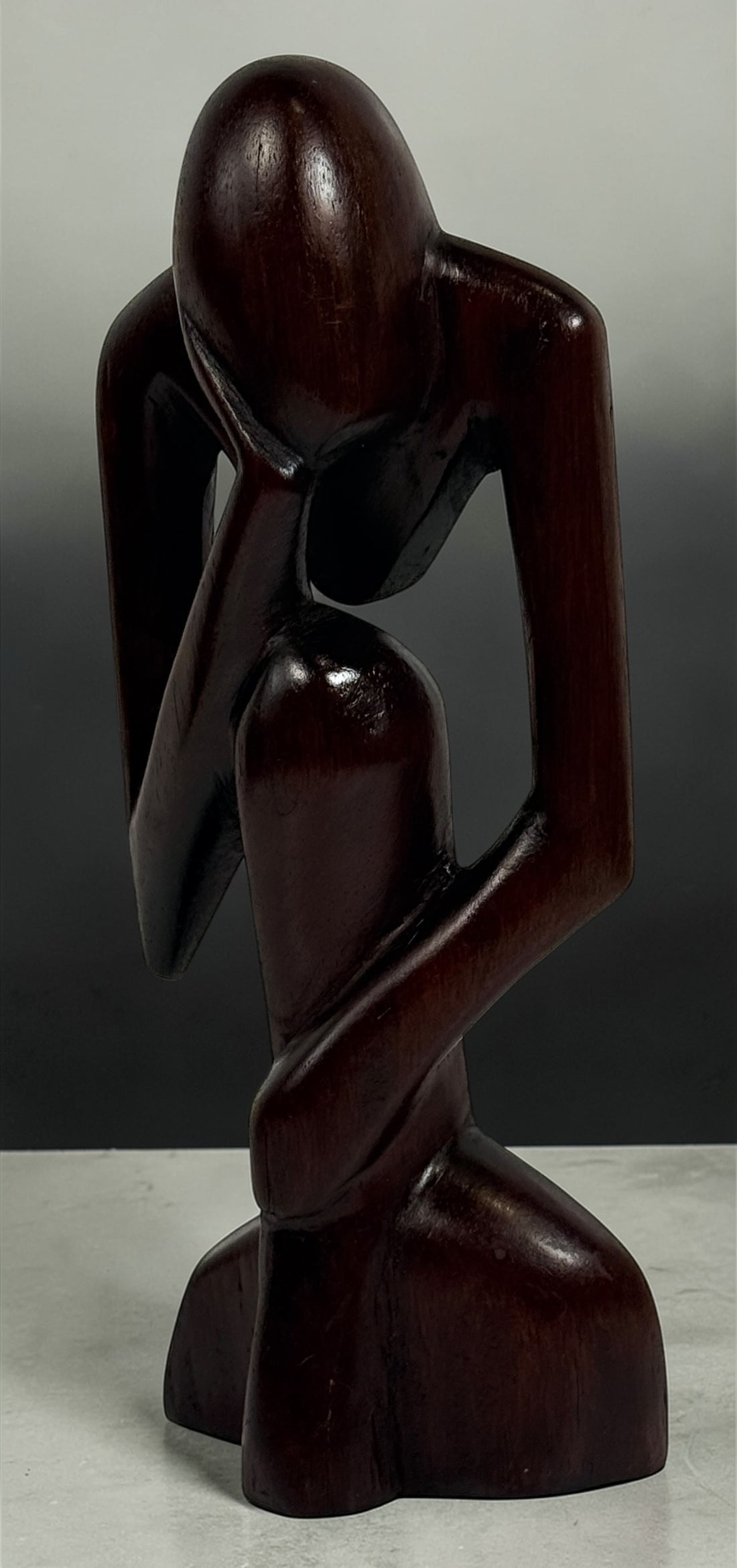 Hand-carved wooden thinker sculpture with mid-century modern style. Abstract decorative figure in dark hardwood, perfect for vintage or contemporary interiors.