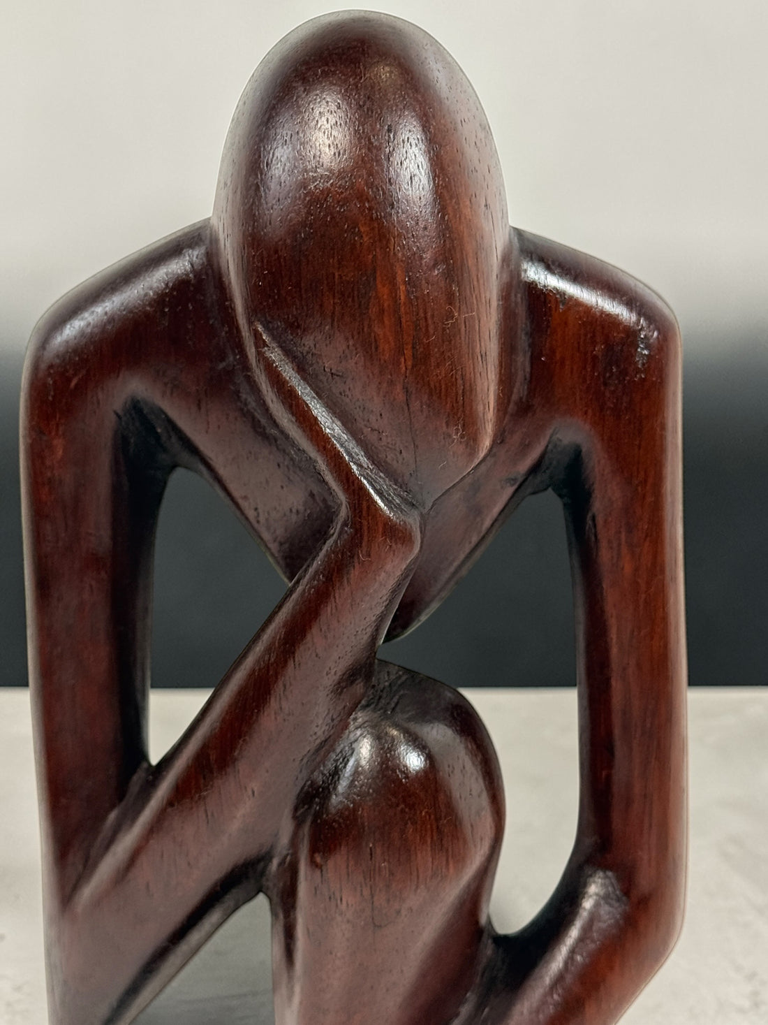 Hand-carved wooden thinker sculpture with mid-century modern style. Abstract decorative figure in dark hardwood, perfect for vintage or contemporary interiors.