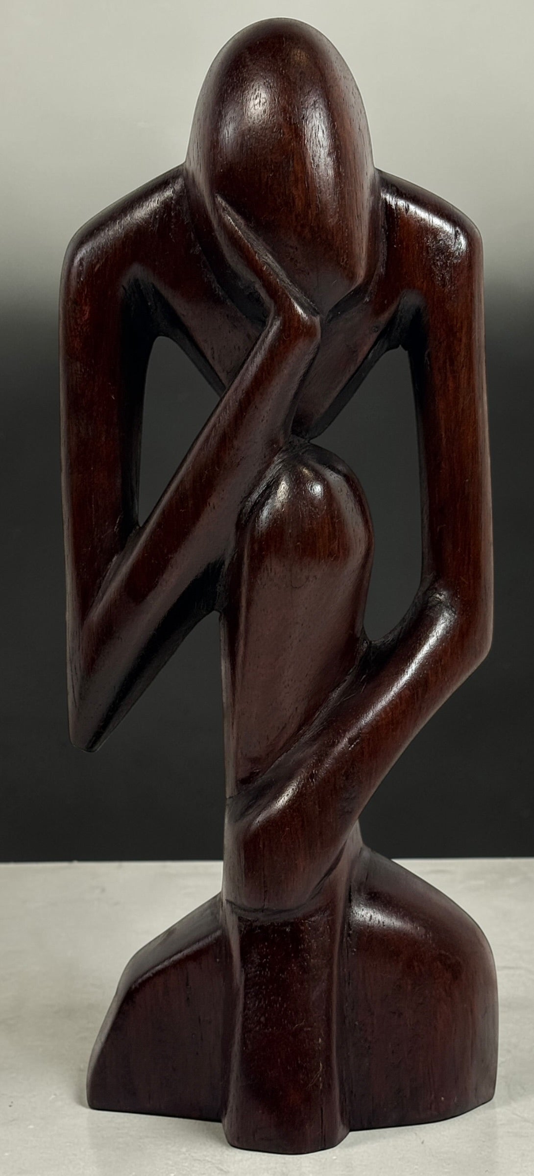 Hand-carved wooden thinker sculpture with mid-century modern style. Abstract decorative figure in dark hardwood, perfect for vintage or contemporary interiors.