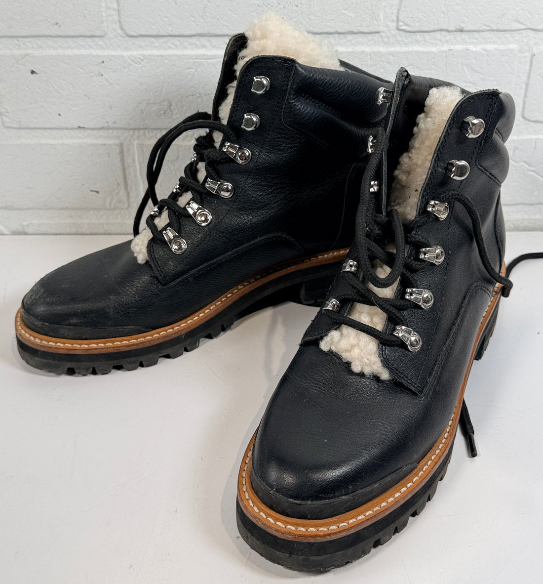 Marc Fisher shearling lined black leather hiking boots size 9M. Rugged winter lace-up ankle boots with lug soles and warm lining, pre-owned condition.
