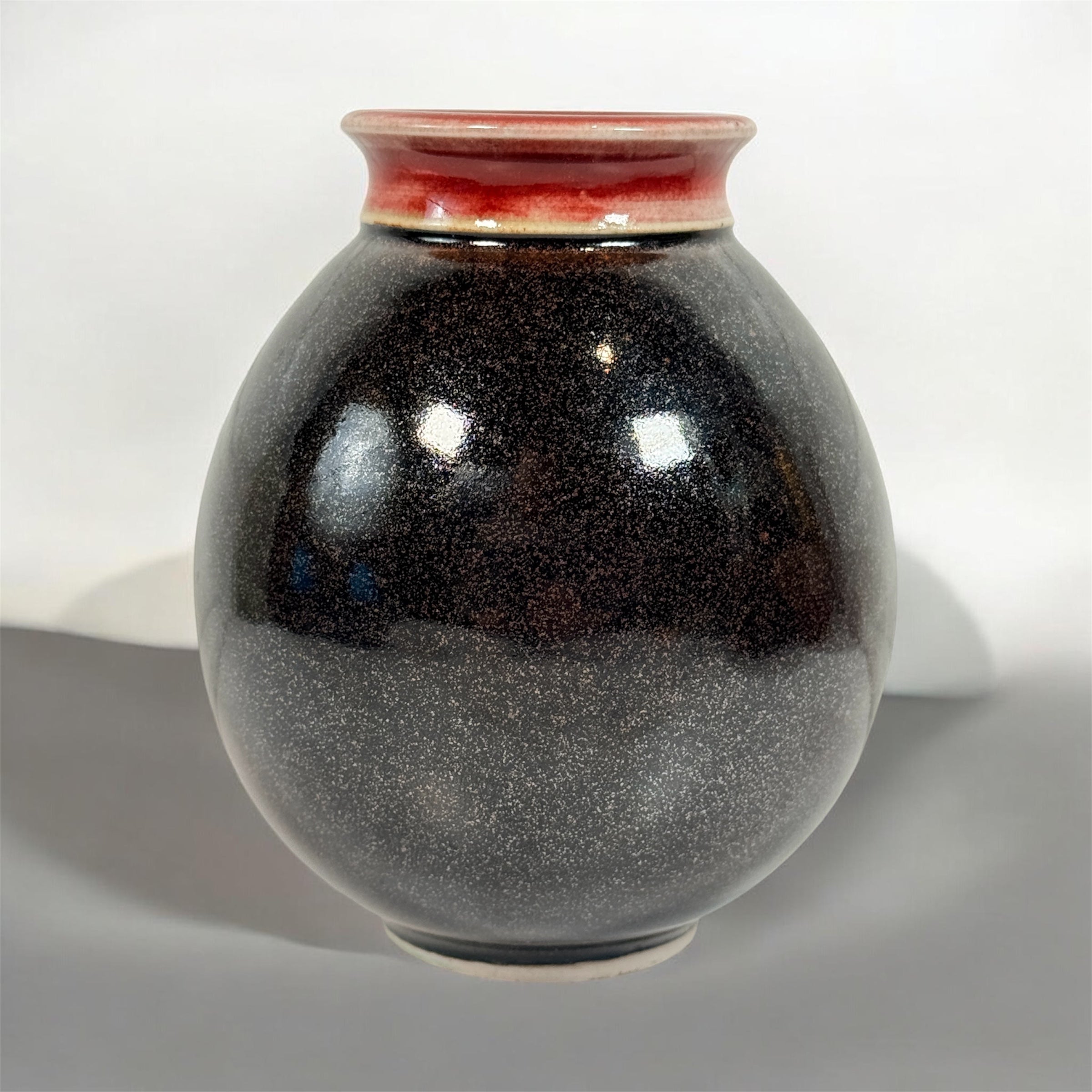 Elizabeth Wolcott signed Canadian studio pottery vase with black glaze and oxblood rim. Handmade ceramic art vase collectible decor piece.