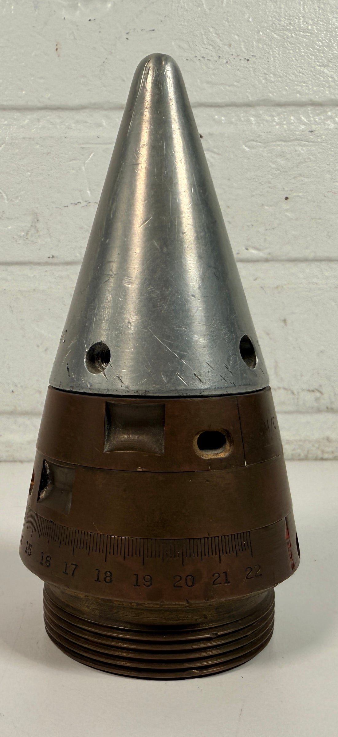 WWII British mechanical time fuze Mk IV brass and aluminum artillery nose assembly. Authentic militaria collectible with timer dial and industrial display appeal.