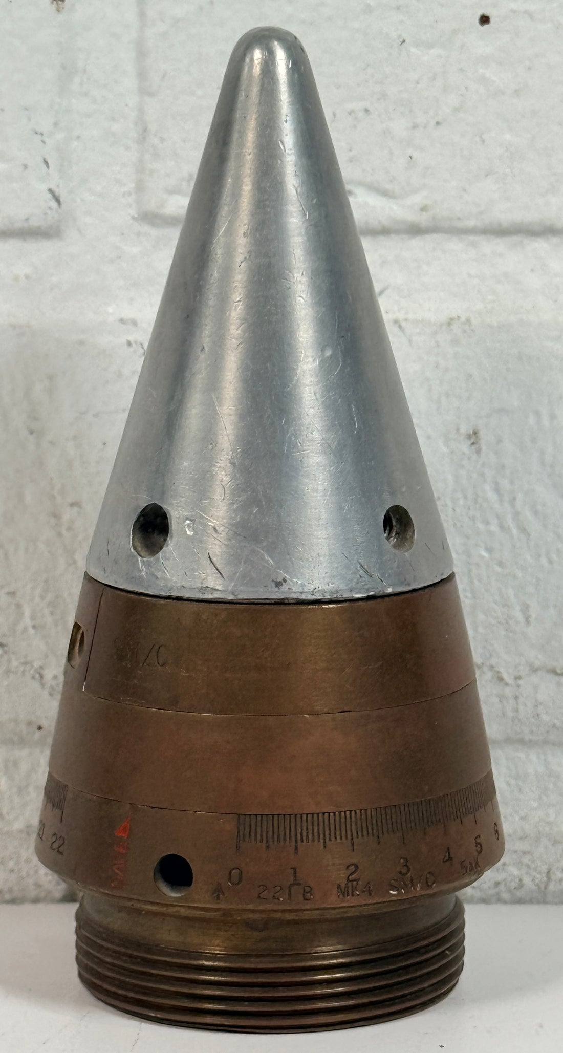 WWII British mechanical time fuze Mk IV brass and aluminum artillery nose assembly. Authentic militaria collectible with timer dial and industrial display appeal.