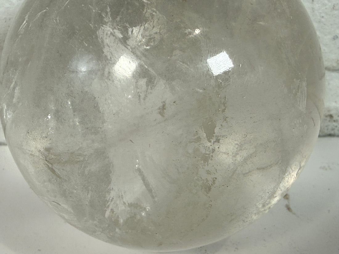 Natural clear quartz crystal sphere 70mm polished orb with beautiful internal veils and inclusions. Decorative display piece for collectors or décor.