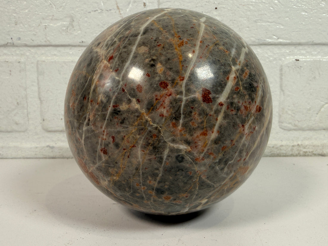 Grande sphère en jaspe gris poli, inclusions de fer rouge, 10 cm