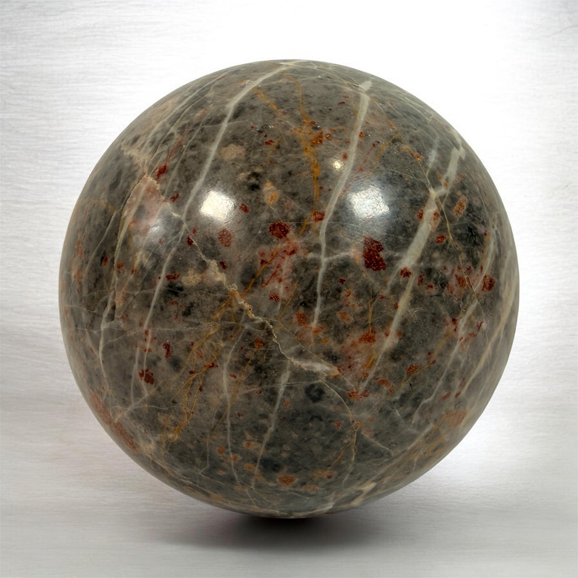 Grande sphère en jaspe gris poli, inclusions de fer rouge, 10 cm