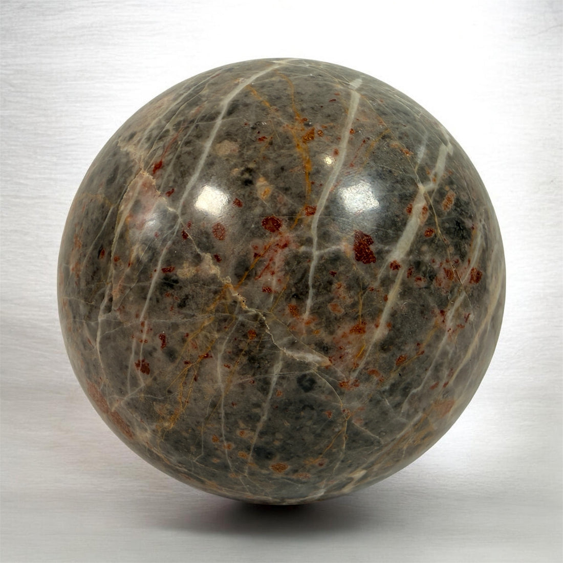 Grande sphère en jaspe gris poli, inclusions de fer rouge, 10 cm
