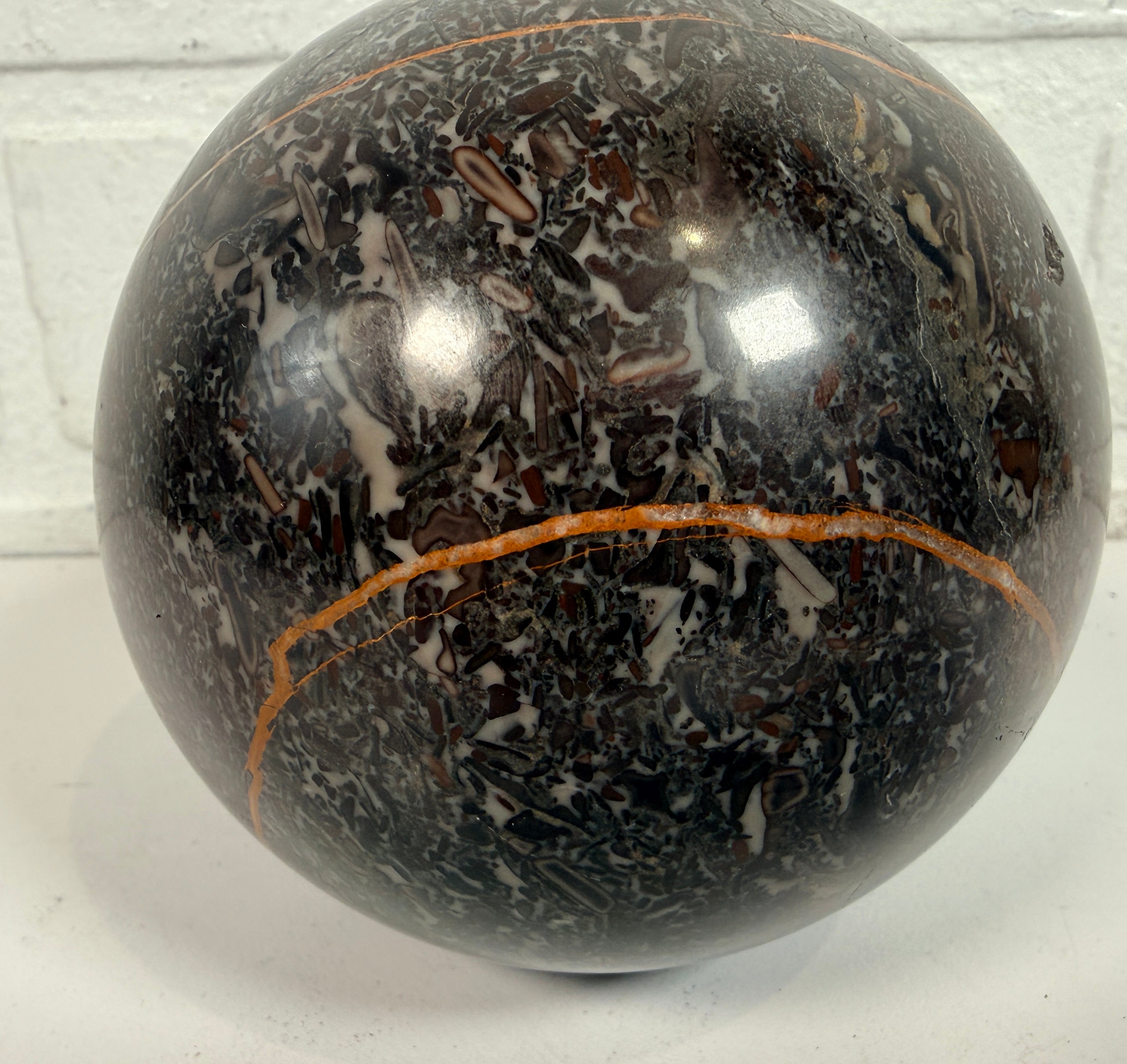 Large Orthoceras fossil sphere from Morocco with visible prehistoric shell fossils in polished black stone. Natural history décor collectible display piece.