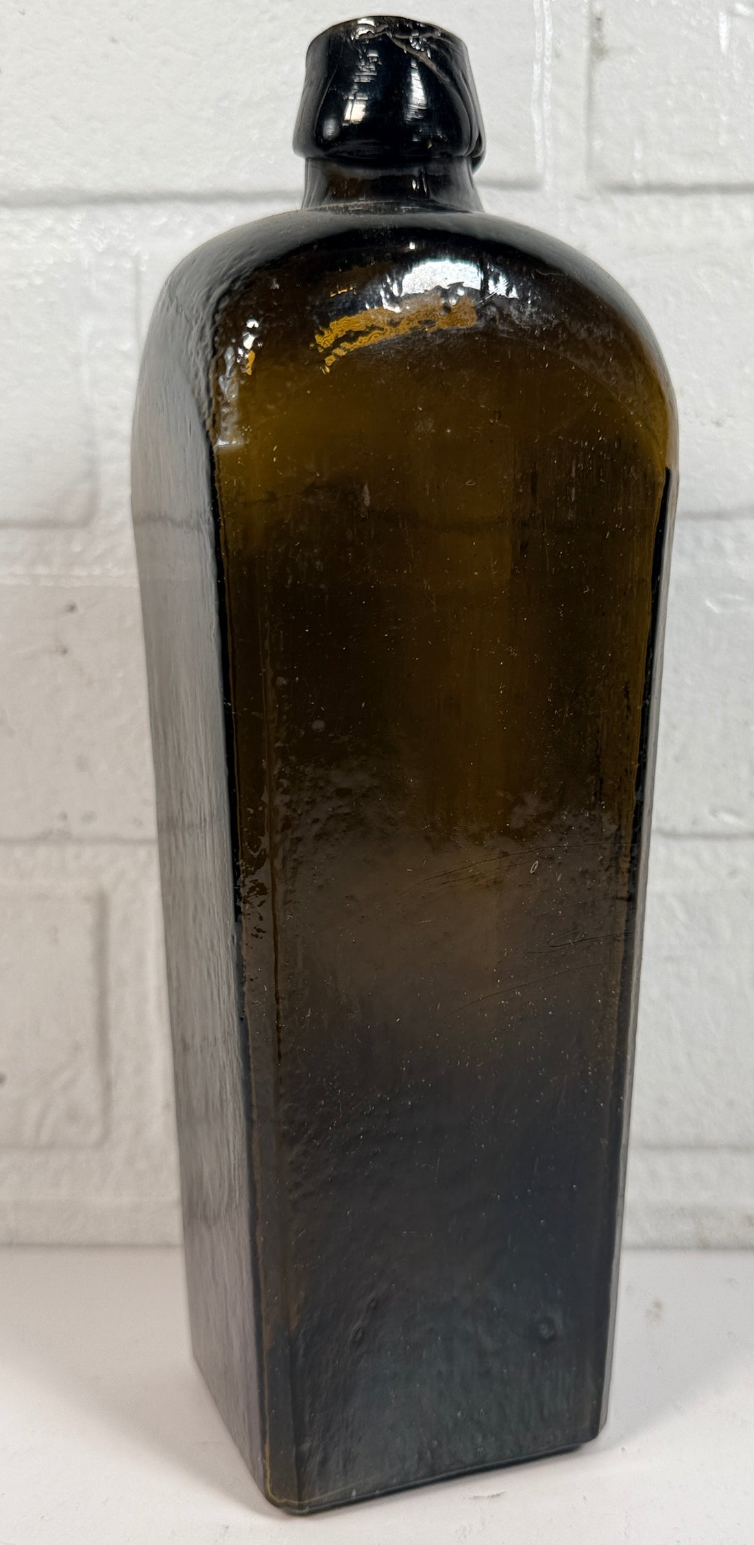 Collectible olive glass Case Gin bottle in classic Dutch jenever style. Square tapered vintage bottle perfect for bar decor, bottle collectors, and display.