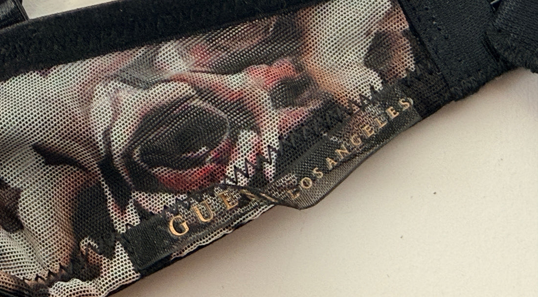 Close-up of a Guess cap with floral design and brand name on a white background