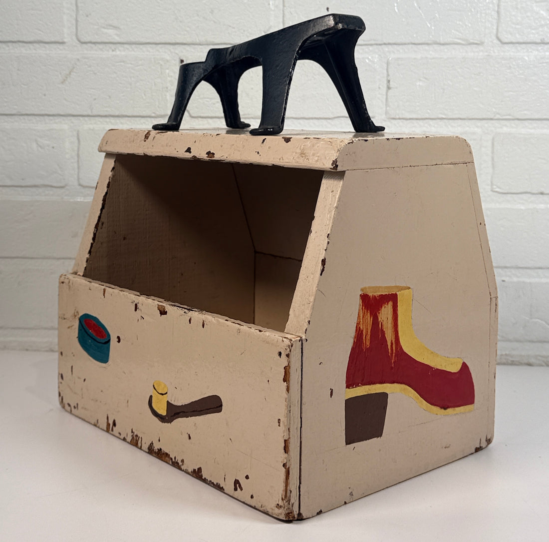 Vintage folk art shoe shine box with cast iron footrest handle. Rustic wooden cobbler caddy with hand-painted details, perfect for decor or storage.