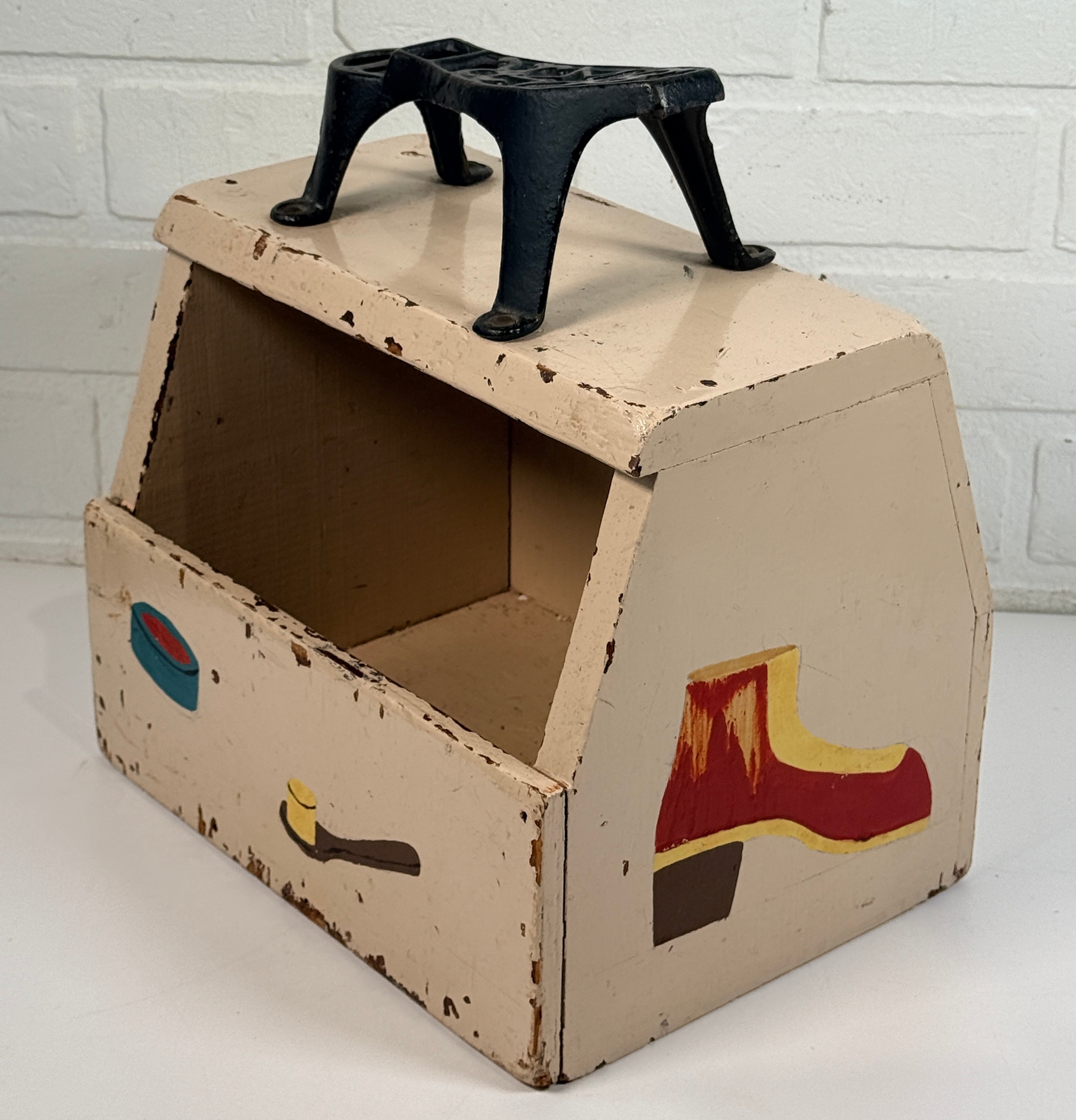 Vintage folk art shoe shine box with cast iron footrest handle. Rustic wooden cobbler caddy with hand-painted details, perfect for decor or storage.