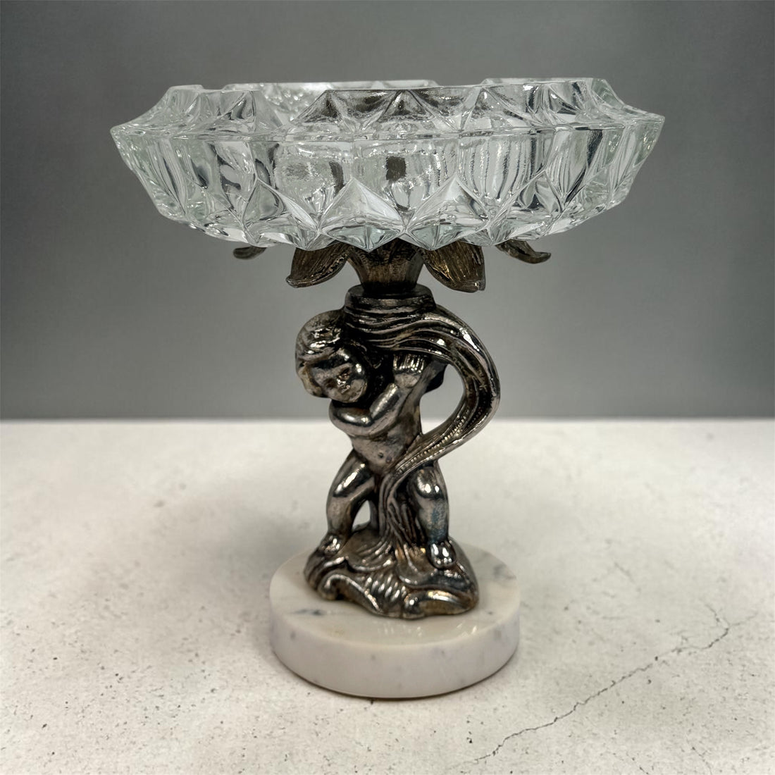 Vintage Hollywood Regency cherub pedestal dish with glass bowl and marble base. Elegant mid-century décor perfect for trinkets, candy, or display.