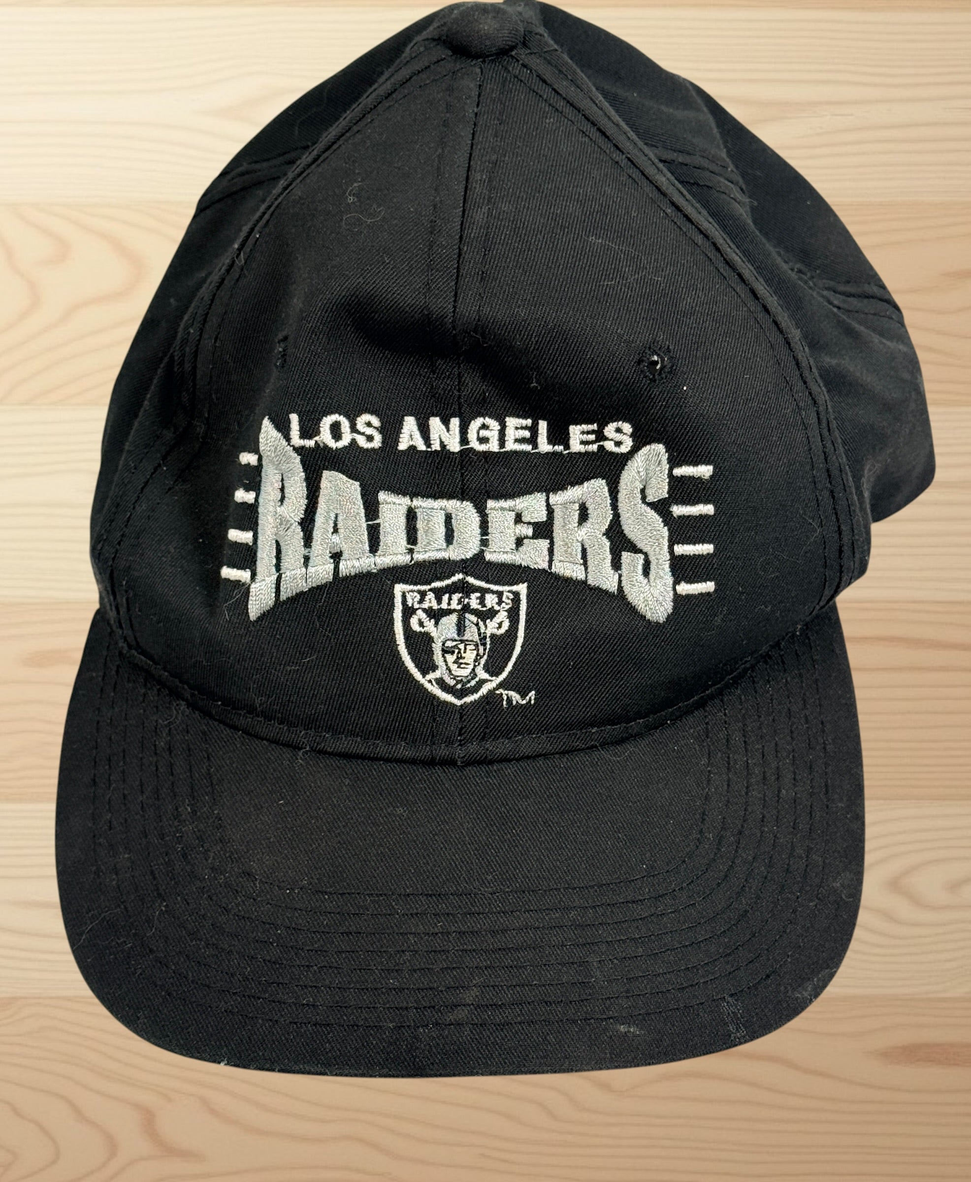 Vintage Los Angeles Raiders snapback hat with green undervisor and embroidered NFL football graphics from the early 1990s.