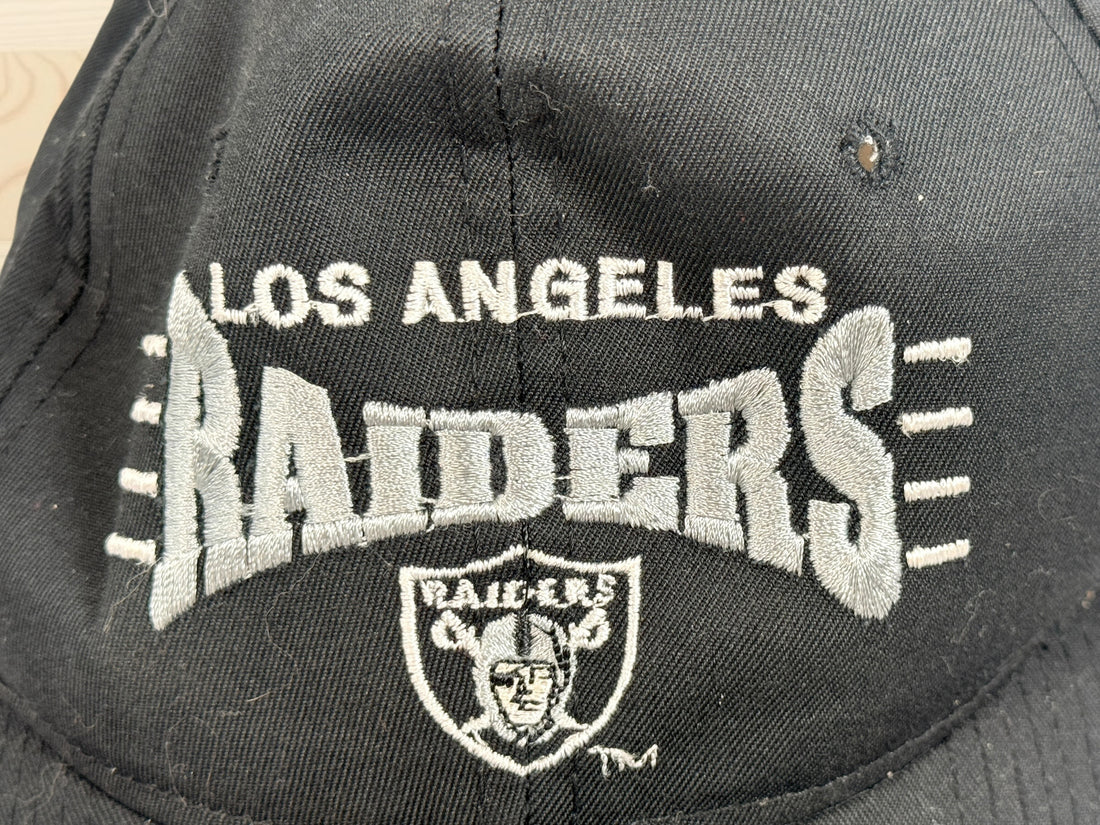 Vintage Los Angeles Raiders snapback hat with green undervisor and embroidered NFL football graphics from the early 1990s.