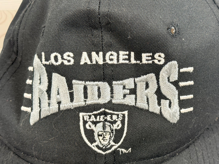 Vintage Los Angeles Raiders snapback hat with green undervisor and embroidered NFL football graphics from the early 1990s.