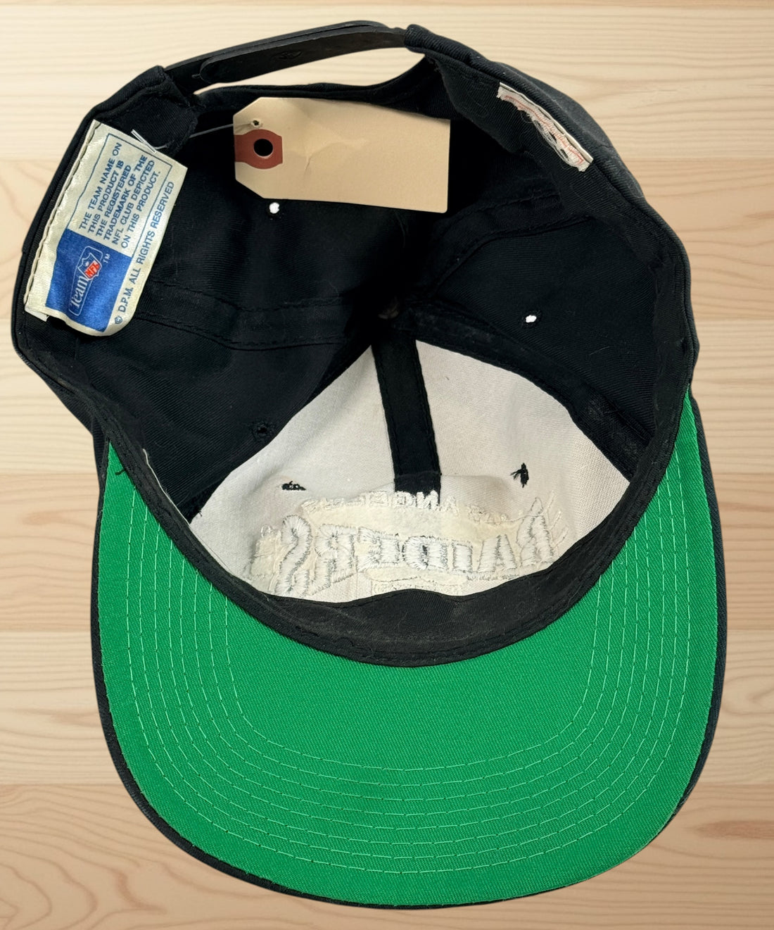 Vintage Los Angeles Raiders snapback hat with green undervisor and embroidered NFL football graphics from the early 1990s.