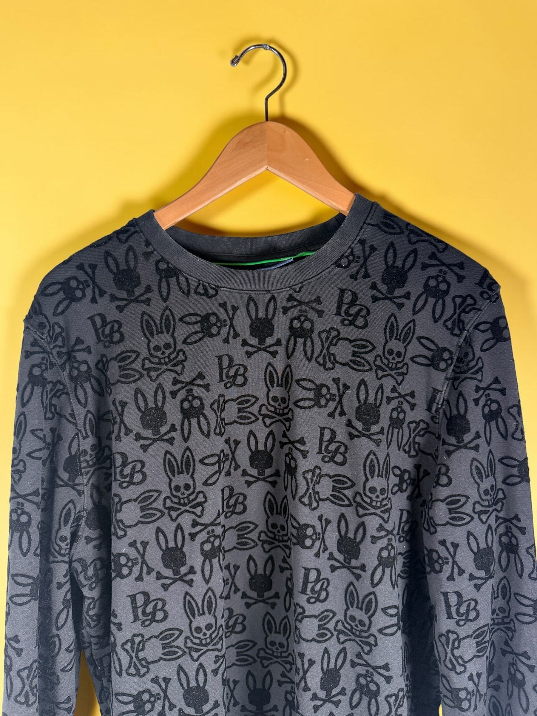 Psycho Bunny skull logo sweatshirt in charcoal grey with all-over flocked graphic print and slim modern streetwear fit.