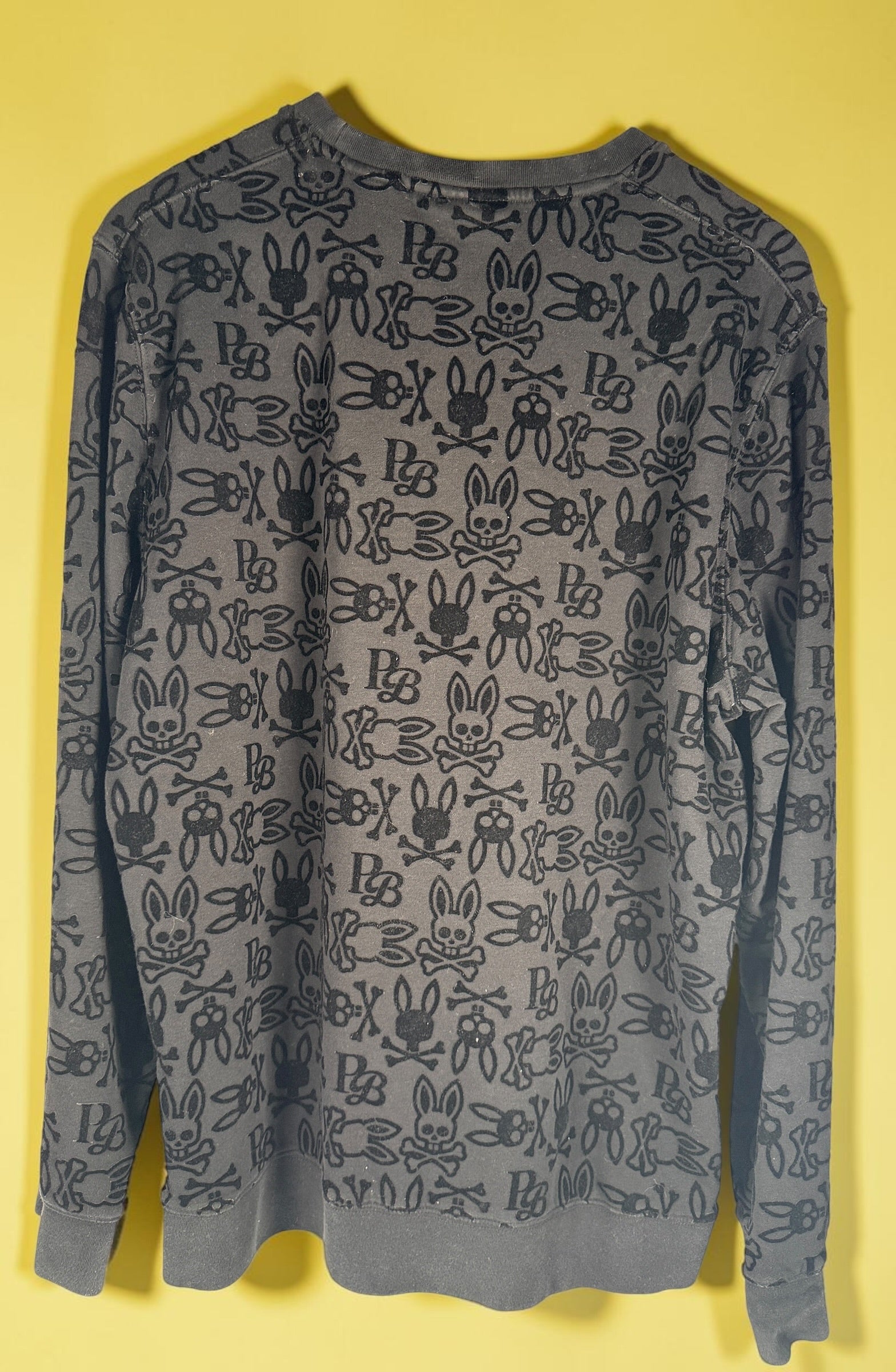 Psycho Bunny skull logo sweatshirt in charcoal grey with all-over flocked graphic print and slim modern streetwear fit.