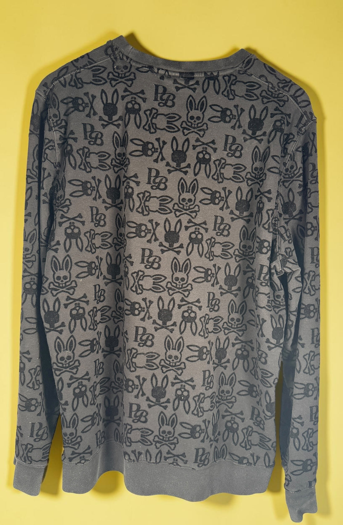 Psycho Bunny skull logo sweatshirt in charcoal grey with all-over flocked graphic print and slim modern streetwear fit.