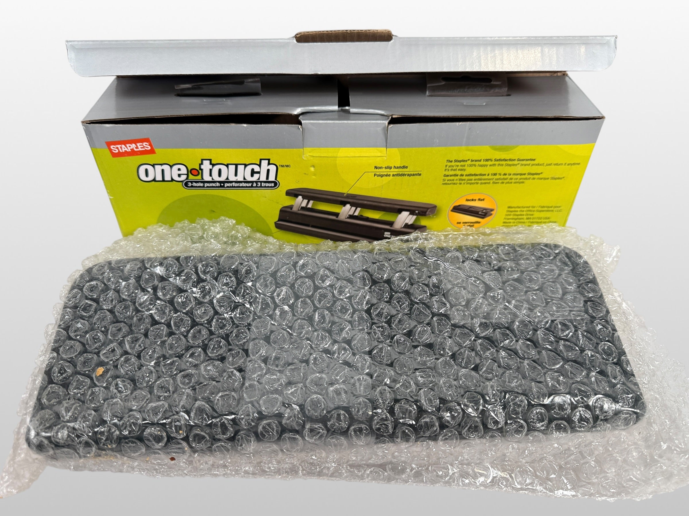 Staples One-Touch 3-hole punch model 26612 with 20-sheet capacity in open-box condition. Includes original packaging and locking flat design.