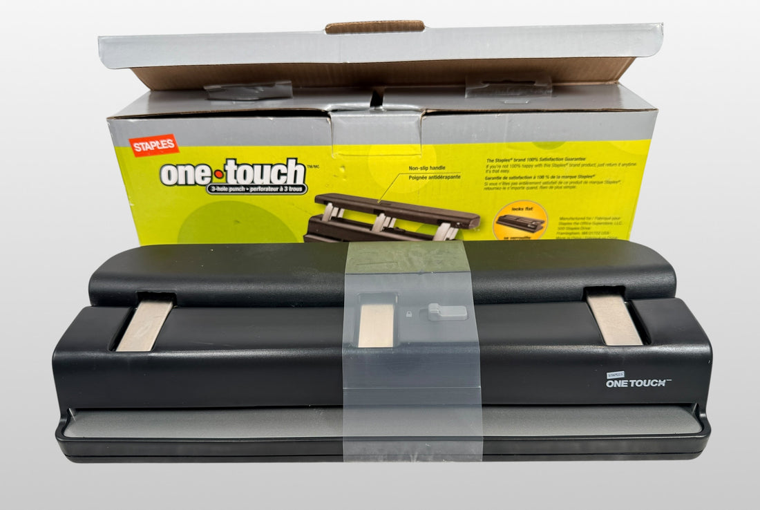 Staples One-Touch 3-hole punch model 26612 with 20-sheet capacity in open-box condition. Includes original packaging and locking flat design.