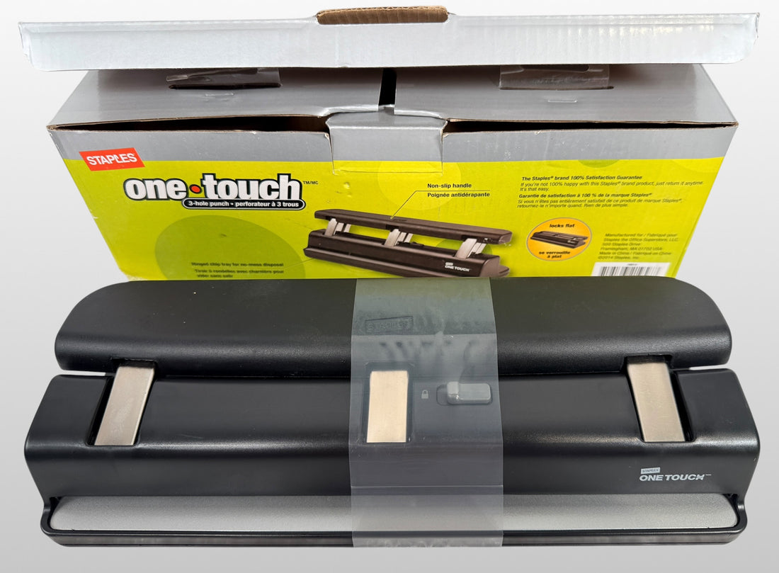 Staples One-Touch 3-hole punch model 26612 with 20-sheet capacity in open-box condition. Includes original packaging and locking flat design.