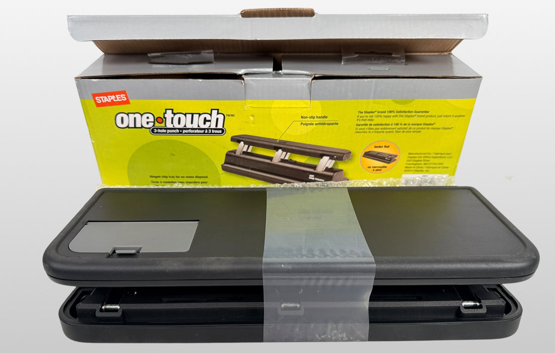 Staples One-Touch 3-hole punch model 26612 with 20-sheet capacity in open-box condition. Includes original packaging and locking flat design.