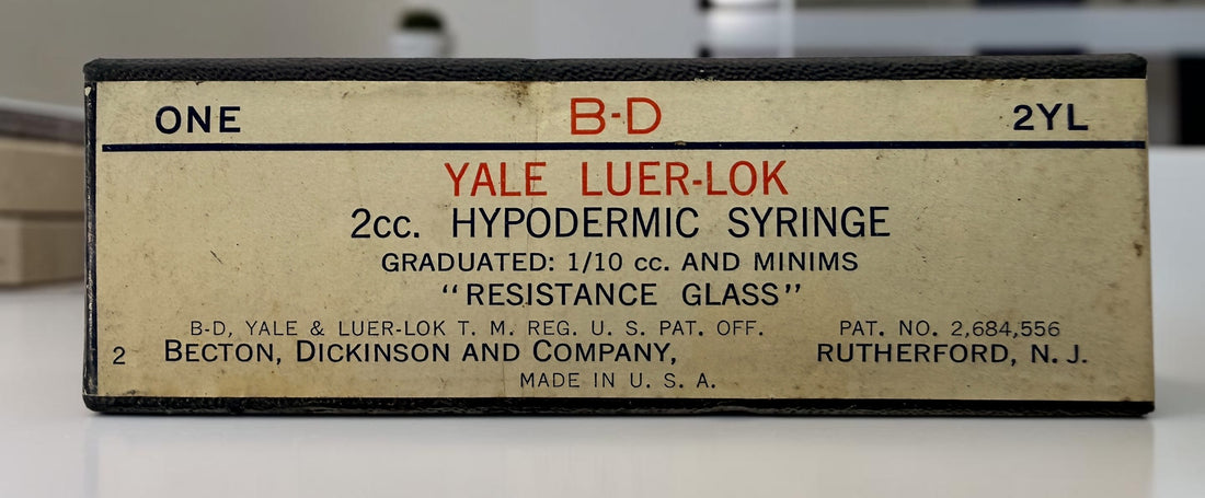Vintage BD Yale Luer-Lok glass hypodermic syringe with original box. Mid-century medical collectible made in USA for apothecary or scientific display.