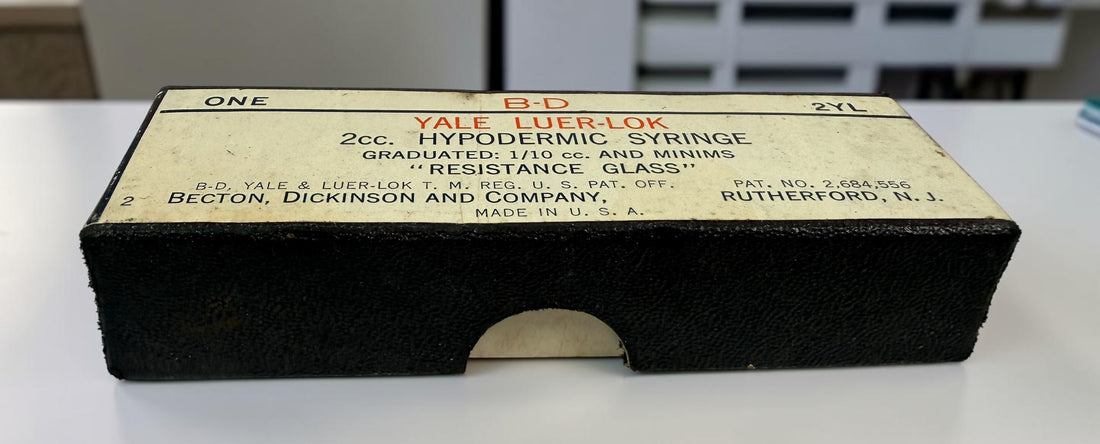 Vintage BD Yale Luer-Lok glass hypodermic syringe with original box. Mid-century medical collectible made in USA for apothecary or scientific display.